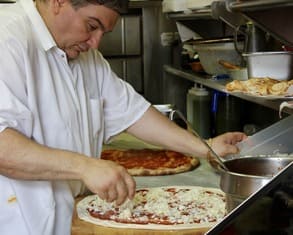 gio tops a pizza with mozzarella