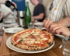 a pizza lover tries to take a slices of beautiful Neapolitan pizza margherita