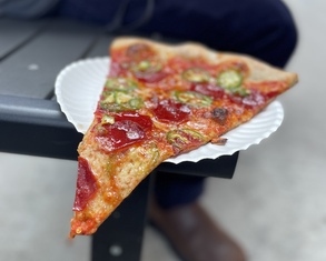 pizza slice hanging off a paper plate