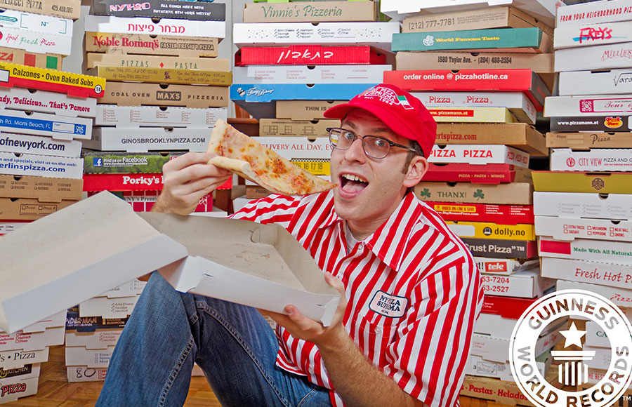 scott eating a slice in front of pizza boxes