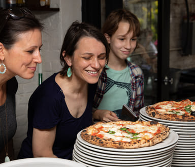 three women smelling a fresh wood fired Neapolitan pizza