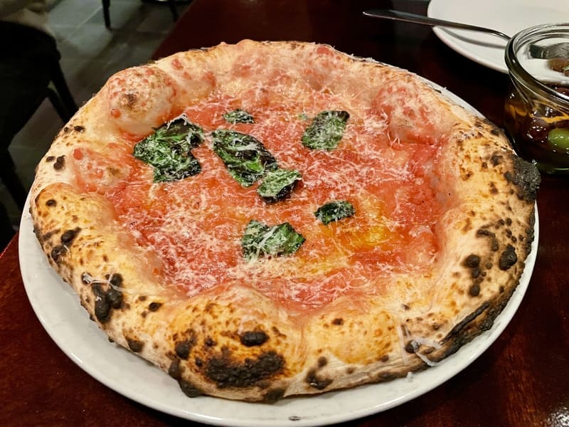 A Neapolitan pizza with a puffy crust, tomato sauce, grated cheese, and basil from Una Pizza Napoletana in New York City