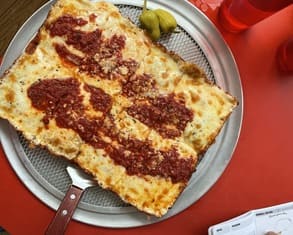 a beautiful rectangular pizza with sauce on top