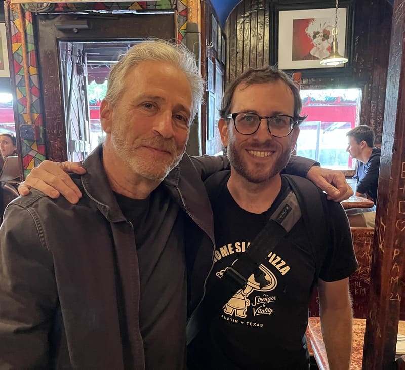 two men stand in a warm embrace of friendship in a pizzeria