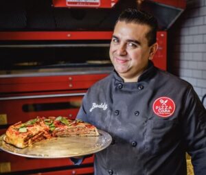 a man smiles while holding a pizza