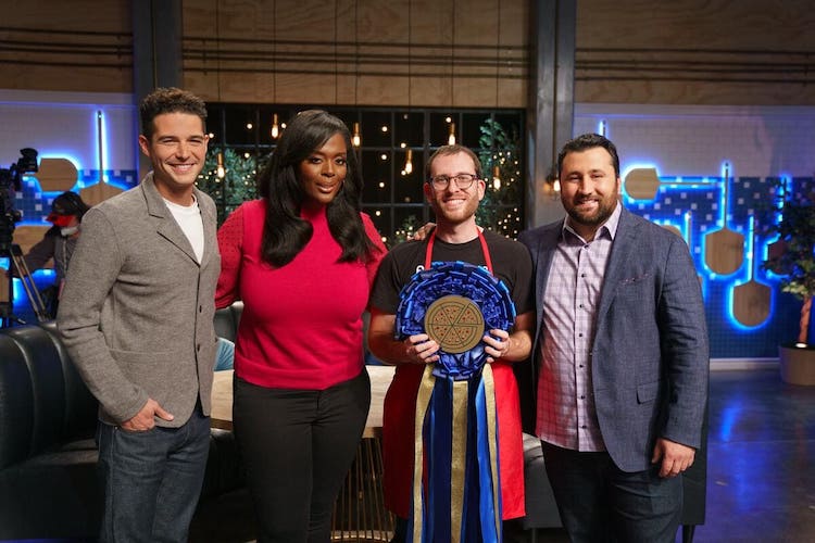 four people stand with a blue ribbon