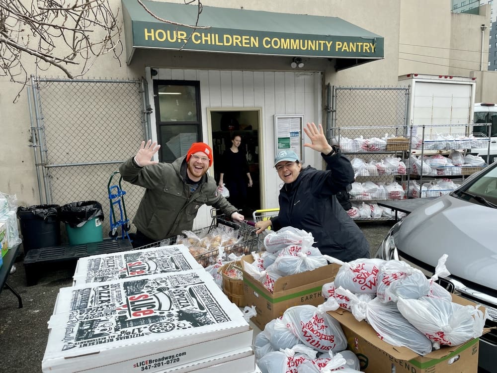 two volunteers pack food donations and pizza slices