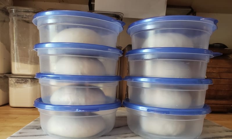 stacks of pizza dough in plastic containers