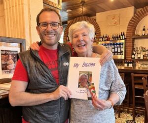 a man with a beard standing with a short haired woman holding a book