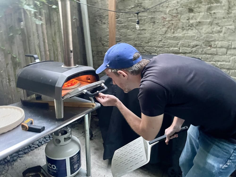 man looking into an outdoor pizza oven
