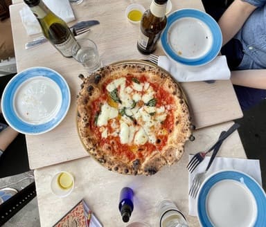 pizza margherita on a table surrounded by people and beers
